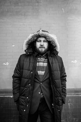 Naklejka premium A man with a beard in a warm winter jacket poses for advertising men's clothing in the winter. Advertising of men's clothing