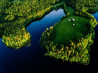 Aerial view of blue lakes and green forests on a sunny summer day in rural Finland.
