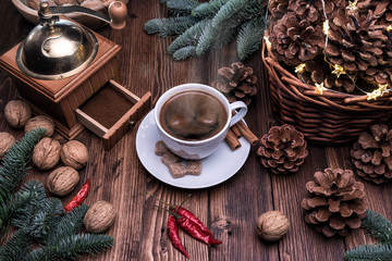 A Cup of fragrant hot coffee surrounded by festive paraphernalia. Old coffee grinder, basket with cones and walnuts