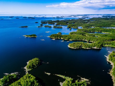 Aerial view of blue lakes and green forests on a sunny summer day in rural Finland.