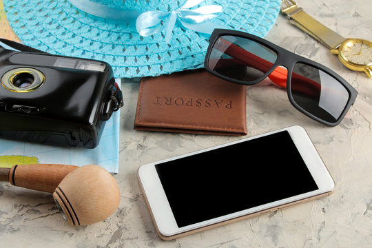 Travel concept Smartphone, passport, map, photo chamber and sunglasses on a light concrete background.