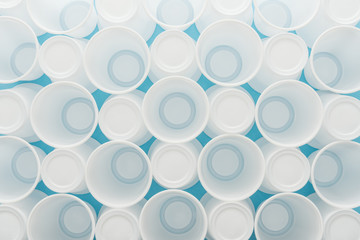 top view of white plastic cups on blue background