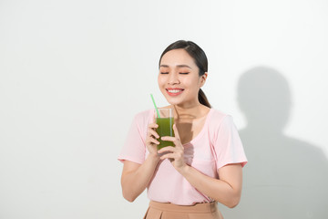 Go green. Young beautiful woman enjoying a healthy raw fruit vegetable juice. Studio shot.
