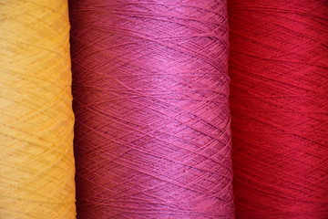 Large bobbins of polypropylene yarn. Large reels Orange, Pink and Red yarns, close up, selective focus. Fragment of bobbins of red and pink thread