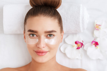 Obraz na płótnie Canvas Woman with collagen pads under her eyes in spa salon