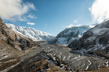 Obraz premium Riverbed in the valley among the snow-capped mountains. Blue sky on the background of snow-capped peaks and riverbed