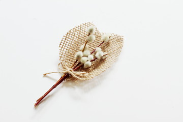 Exclusive bouquet of willow branches on background of decorative leaves of homespun jute fabric on white background. Congratulatory concept for birthday, Valentine's Day, Mother's Day. Minimal style.