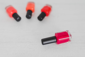 red nail polish bottle and other colors on wooden surface