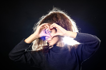 Emotional portrait of a girl with long curly hair on a black background,