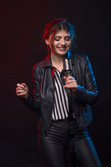 Portrait of expressive rock singer wearing leather jacket and keeping retro style microphone.