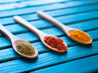 Different spices in spoons on wooden background