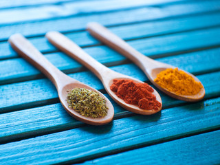 Different spices in spoons on wooden background