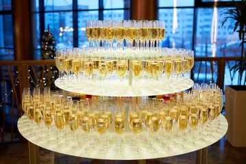 Radial staging of gold champagne glasses on a three-tier table in a restaurant.
