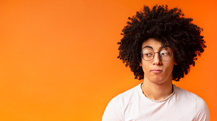 Skeptical young man looking aside at free space