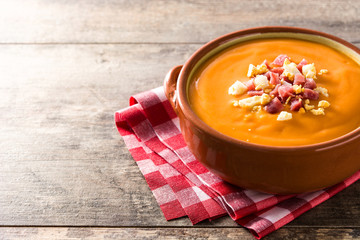 Typical Spanish salmorejo cream with ham and egg on wooden table. Copyspace
