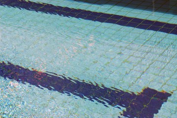 Summer day at swimming pool. Background and texture concept. Ripple Water in swimming pool with sun...