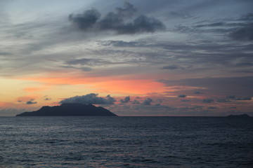 uninhabited island in the ocean against the red sunset