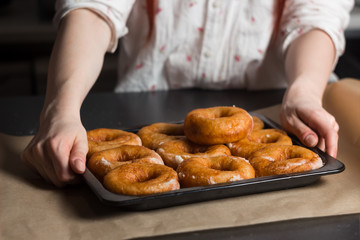 fresh donuts on a tray, sugar puffs from the oven on a tray, yeast donuts, a bakery product, donuts in hand, a cook at work