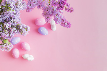 Fototapeta na wymiar Flat lay composition with branches of lilac and easter eggs on a pink background
