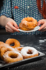 a girl in a vintage shirt with donuts, donuts on a plate, drzhit puffs in her hand, donuts in powdered sugar, donut in hand