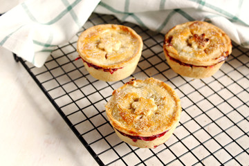 Traditional rustic homemade american  mini cherry pie with golden crust on cooling rack