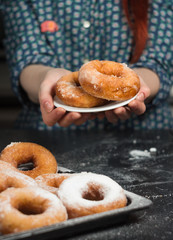 a girl in a vintage shirt with donuts, donuts on a plate, drzhit puffs in her hand, donuts in powdered sugar, donut in hand