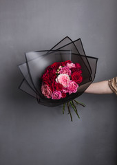 bouquet in hand, against a gray wall, in a transparent gray box with a black border, a lot of roses,
