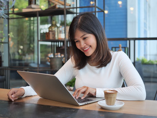 Asian woman using laptop computer in coffee shop cafe