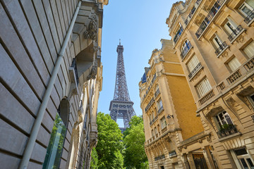 Eiffel Tower and typical street with ancient buildings in Paris in a sunny summer day, clear blue sky
