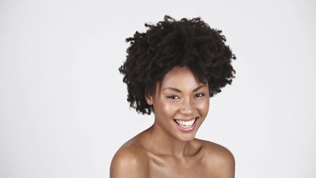 naked beautiful african american girl looking at camera and laughing on white 