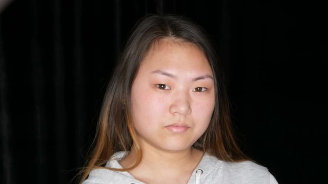 Portrait of a beautiful Asian girl model without makeup who poses in a professional studio