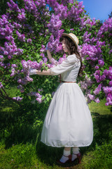 Obraz na płótnie Canvas Girl in a white dress hugs a flowering lilac