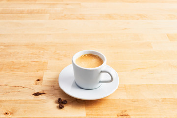 Cup of coffee or espresso and coffee beans on wooden table. Copy space for text.