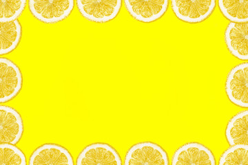 Pattern made from fresh lemon slices on a yellow background with copy space in the middle. Overhead view, flatlay. Fruit background.