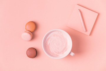 Cup of coffee with macaroons on pastel background.