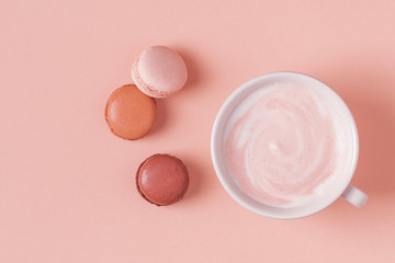 Cup of coffee with macaroons on pastel background.