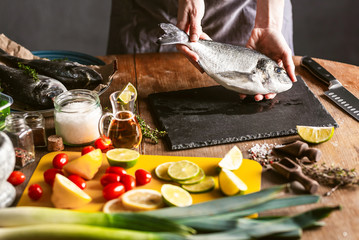 woman chef preparing fresh raw dorado fish