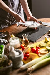 Foto op Canvas woman chef preparing fresh raw dorado fish © Mikhaylovskiy 