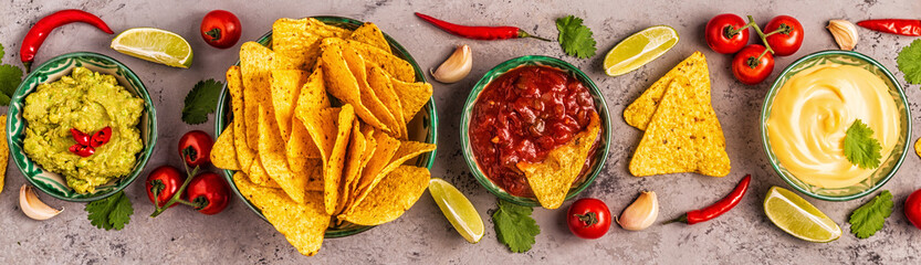 Mexican food background: guacamole, salsa, cheesy sauces with nachos