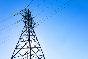 High voltage electricity pylon and transmission power line on the blue sky on the background. Parts...