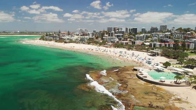 Aerial drone footage of ocean waves on a busy Kings beach, Caloundra, Australia