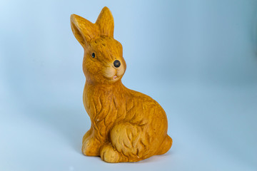 Brown ceramic rabbit in front of a blue background as the basis for an Easter card.