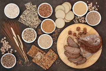 High fibre super food with whole wheat pasta, whole grain walnut and rye bread, crackers, seeds, nuts, grains, oatmeal, oats, barley and bran flakes with wheat sheath on lokta paper background.