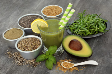 Juice smoothie health drink with avocado, ruccola, basil herb, flax, chia, hemp seed and food supplement powder on rustic wood  background. High in omega 3, antioxidants, vitamins and dietary fibre.