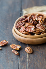 Pecan nuts on a rustic wooden table and pecan nuts in bowl.