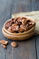 Pecan nuts on a rustic wooden table and pecan nuts in bowl.