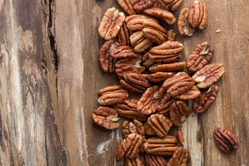 Pecan nuts on a rustic wooden table and pecan nuts in bowl.