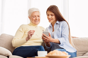 Senior mother and daughter reading news on smartphone