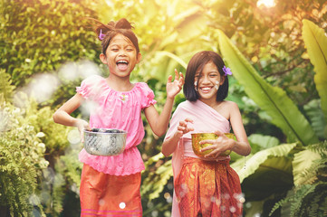 Songkran day with thai girls children playing splash water in songkran festival with thai period dress