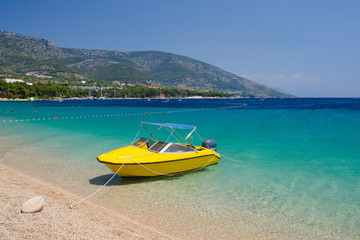 Fototapeta na wymiar Yellow boat near cape Zlatni Rat of Brac Island, Adriatic Sea, Croatia